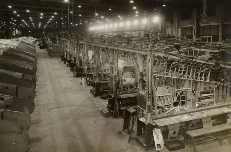 Black and white photo of a vintage factory assembly line with repeating industrial structures.