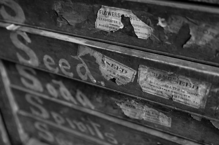 Black and white photo of old industrial drawers with faded labels, symbolizing structured storage and organization.