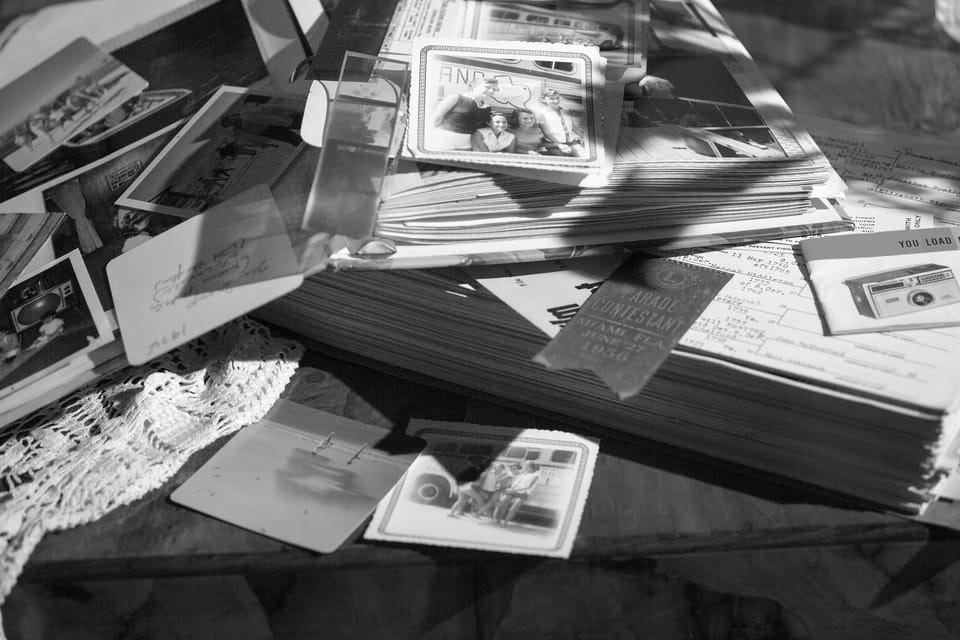 Black and white photo of vintage letters and postcards stacked on a table, symbolizing communication and personal contact.