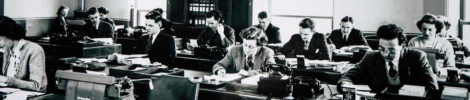 „Schwarz-weiß Fotografie eines Großraumbüros in den 1950er Jahren mit vielen Menschen an Schreibtischen, Symbol für den Wandel von Arbeitswelt und Berufen.“